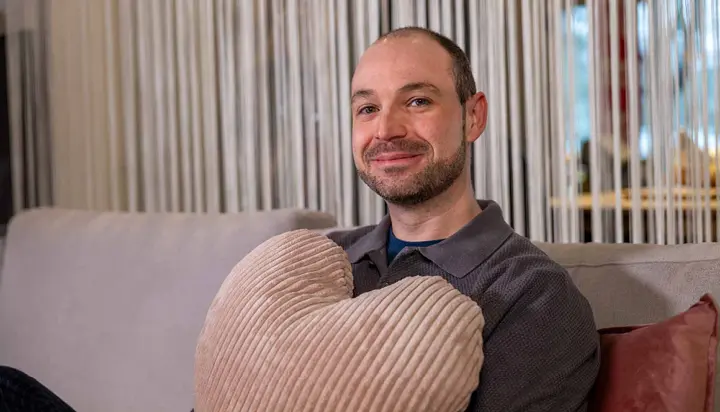 Helles Wohnzimmer mit grauem Ecksofa und Relaxsessel, dekoriert mit bunten Kissen, Pflanzen und Teppich im skandinavischen Stil – modernes Sofa-Design für gemütliches Wohnen.